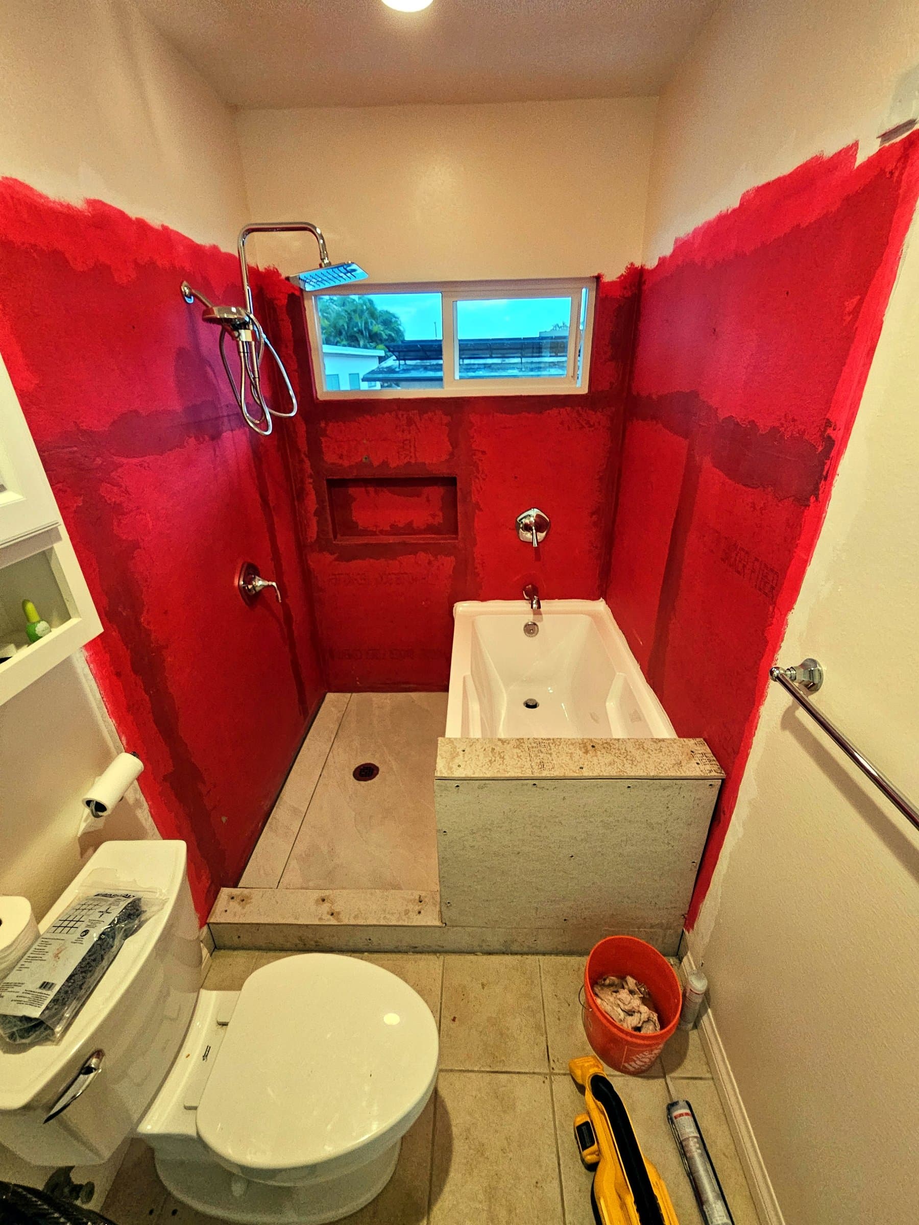 Shower walls with red waterproofing, before tile
