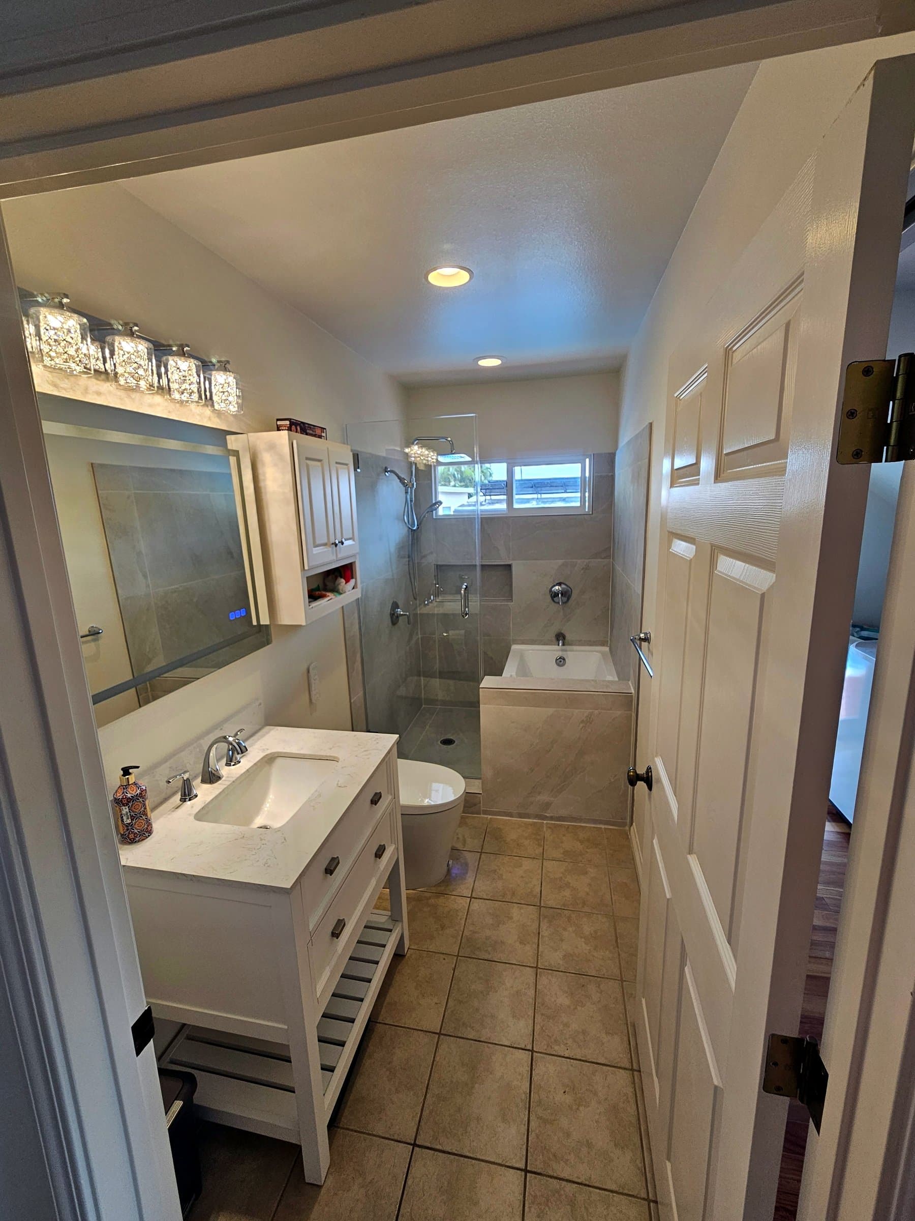 The same bathroom finished: vanity, glass shower, tub