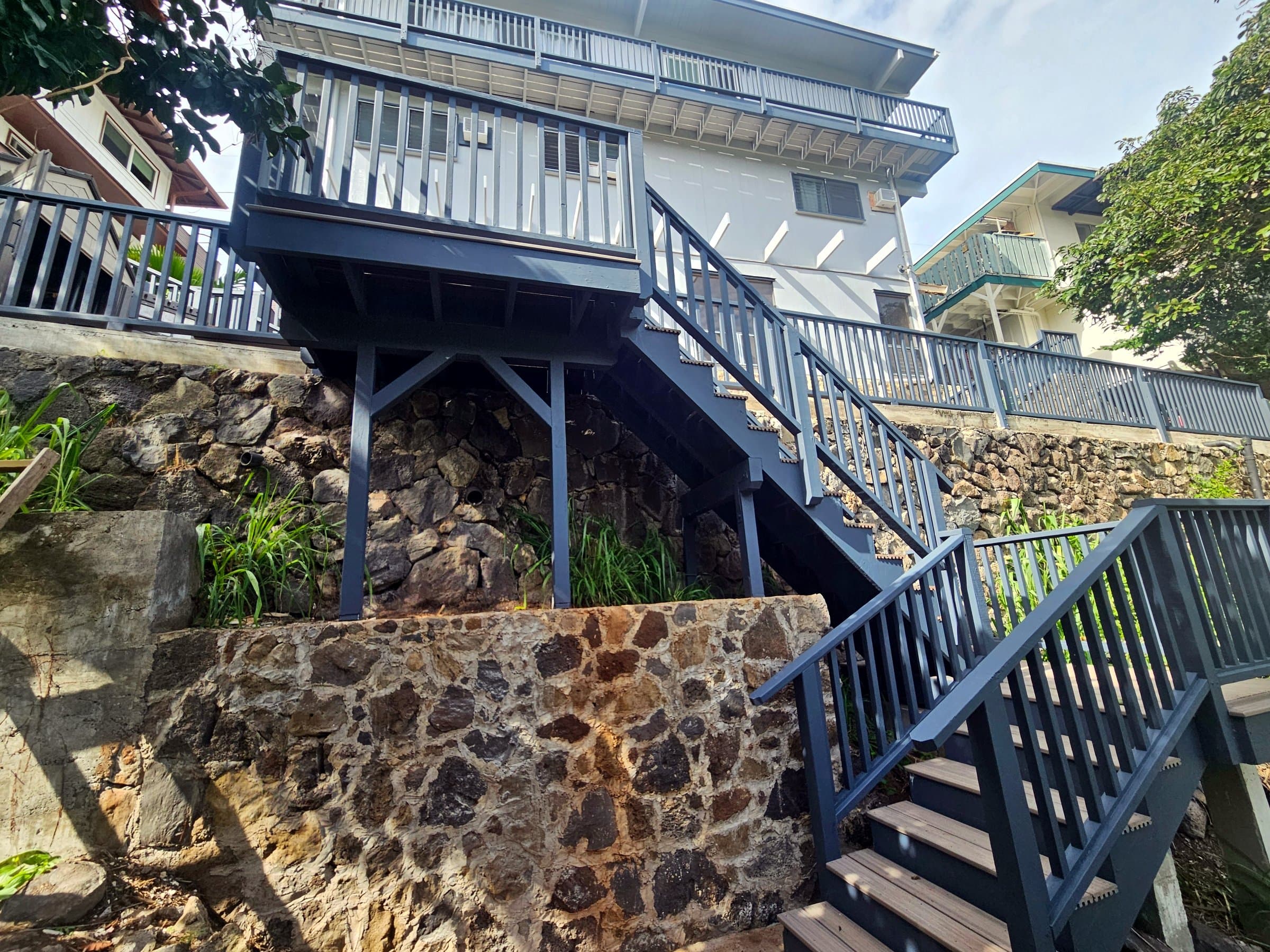 Grey deck and staircase over two lava-rock retaining walls