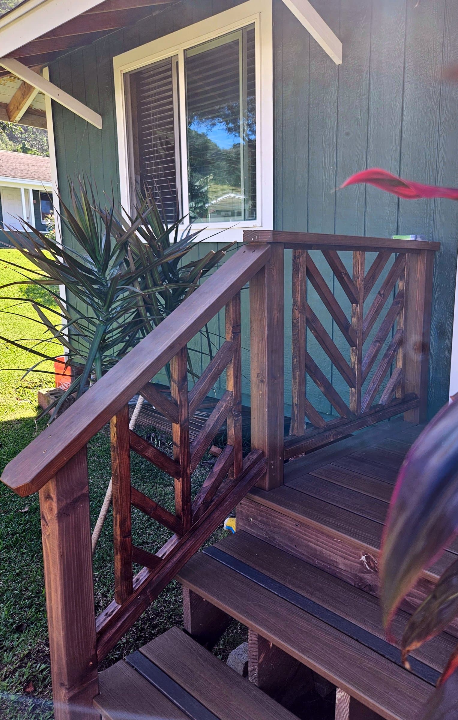 Chevron-pattern wood stair railing on a green cottage