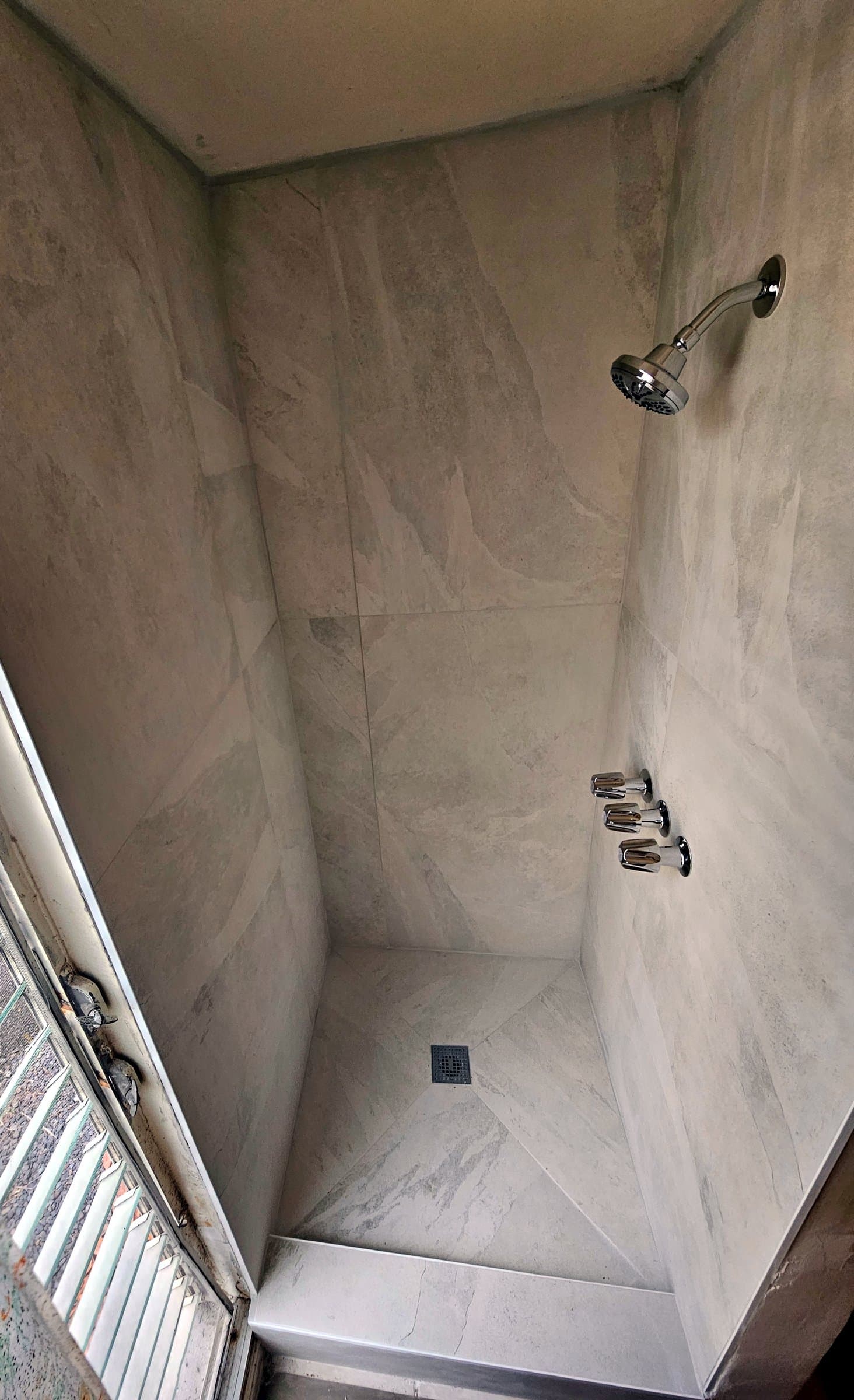 Grey marble-look tiled shower with chrome fixtures
